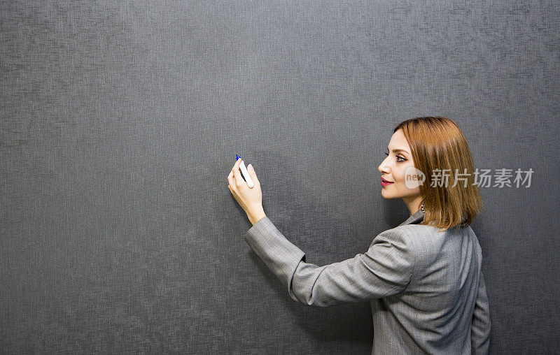 自信的商业女性或在深色黑板上写字的老师。