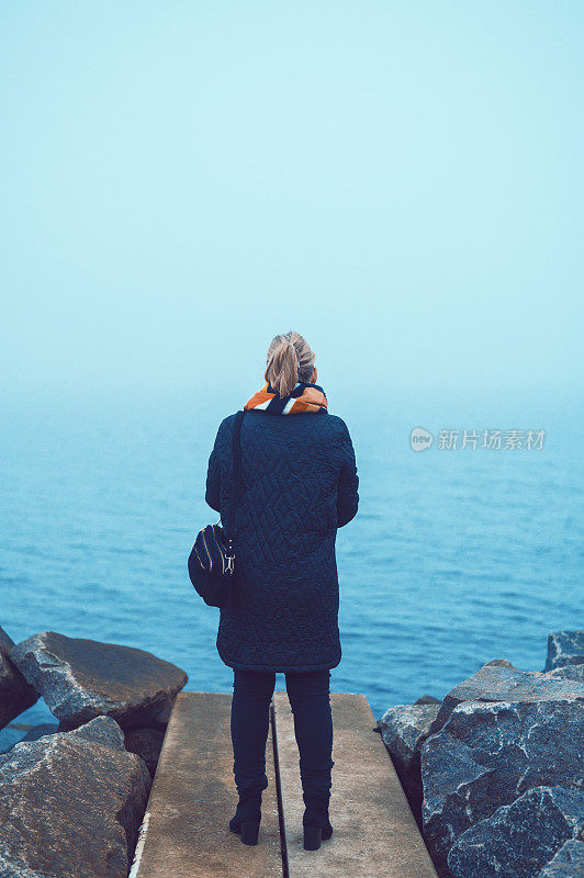 后视图的女性站在海边在一个寒冷和阴天