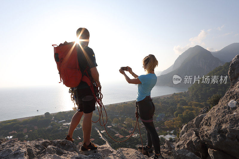 登山运动员在日出时用手机拍照