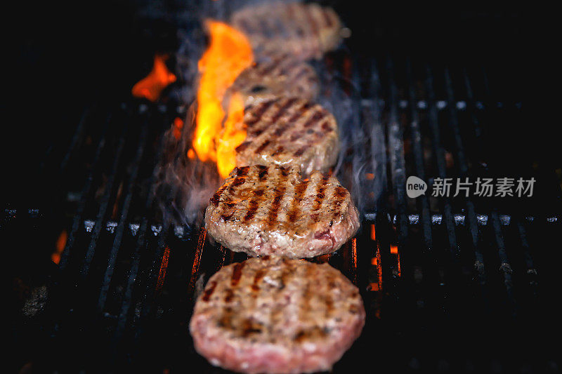 燃烧的牛肉汉堡肉饼在烤架上