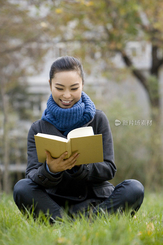 青年女子坐在草地上看书