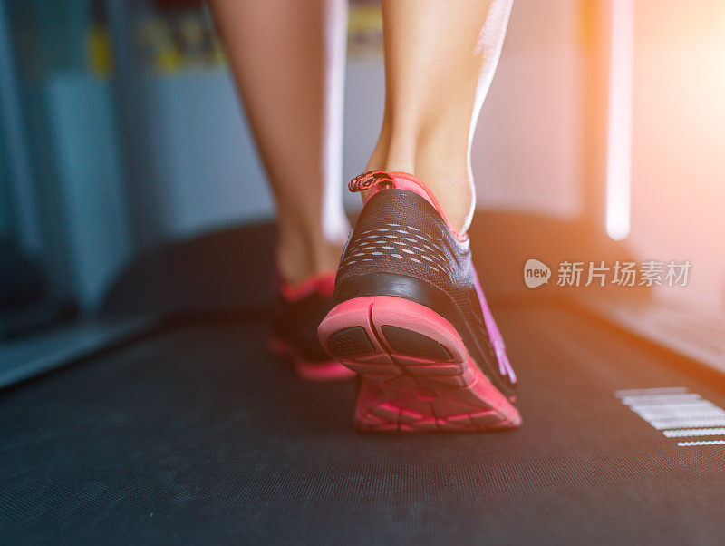 女性肌肉足穿着运动鞋在跑步机上跑步。