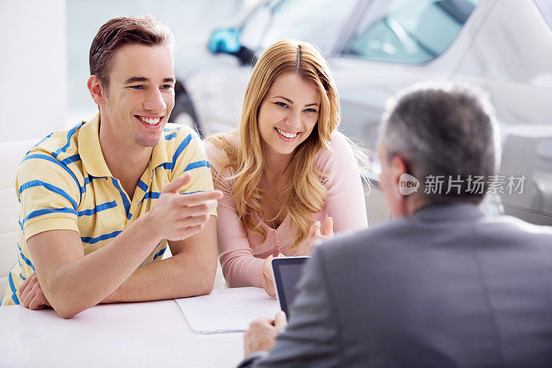 一对夫妇与汽车销售人员交流。