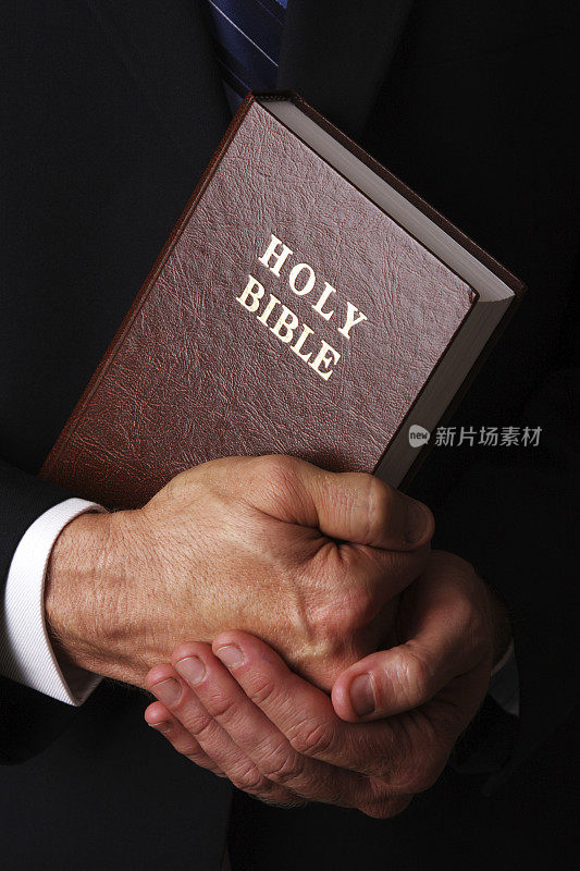男人的手拿着一本精装的圣经
