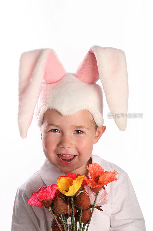男孩的肖像打扮成复活节兔子拿着花笑