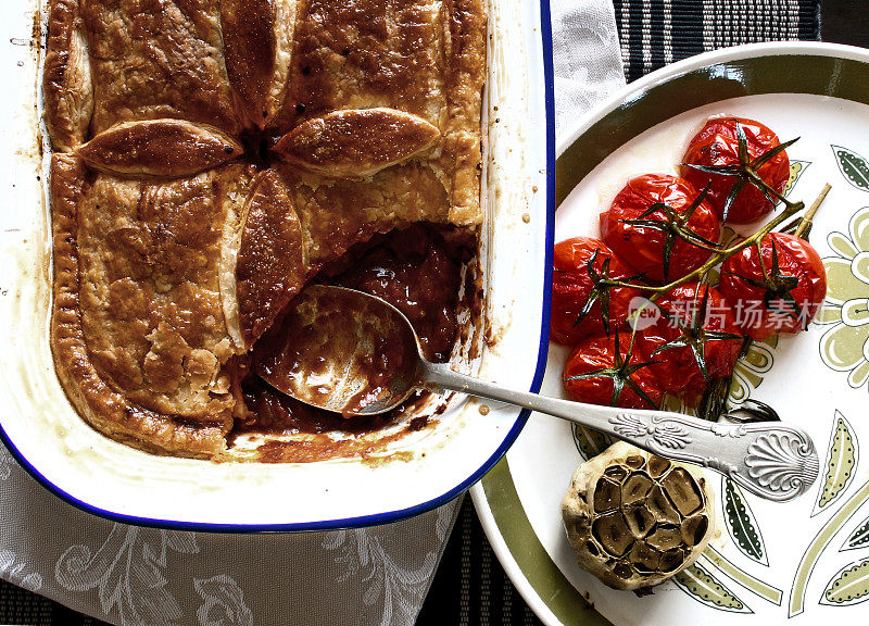 丰盛的肉派配烤大蒜和樱桃番茄