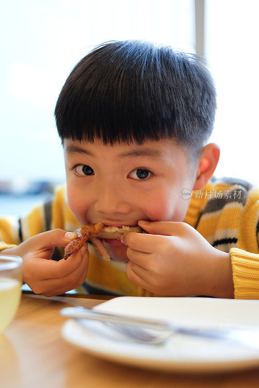 一个亚洲男孩在餐厅吃午饭