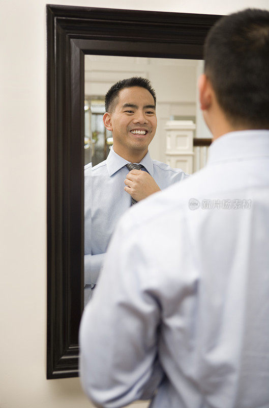 亚洲男人在镜子前系领带
