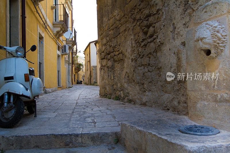 拉古萨伊布拉，西西里岛:有喷泉和老式摩托车的狭窄小巷