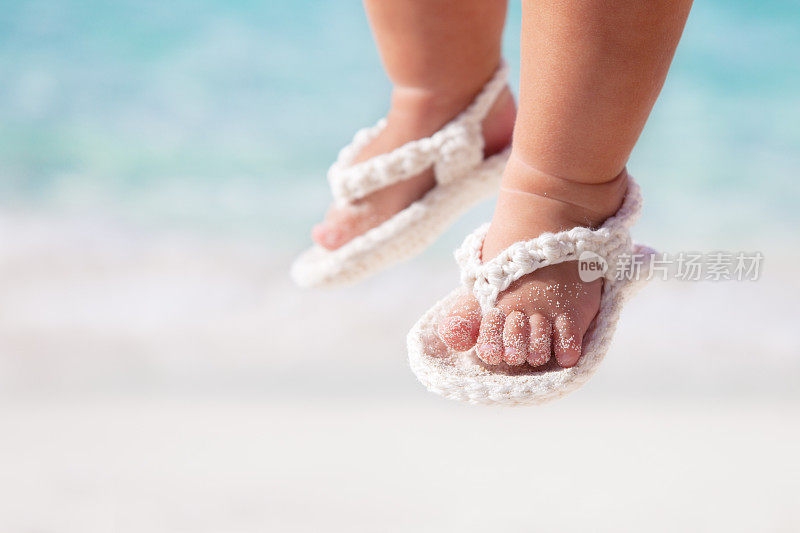 在加勒比海滩上穿着白色凉鞋的婴儿脚