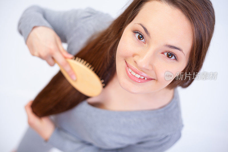 一位年轻女子微笑着梳着头发。