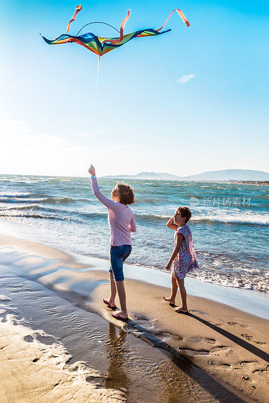 两个可爱的女孩在海滩上放风筝