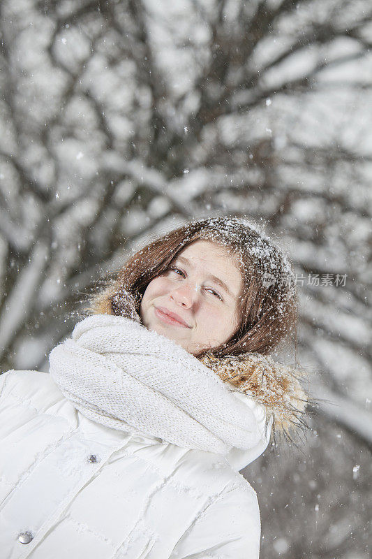 雪下穿着白色夹克的漂亮少女