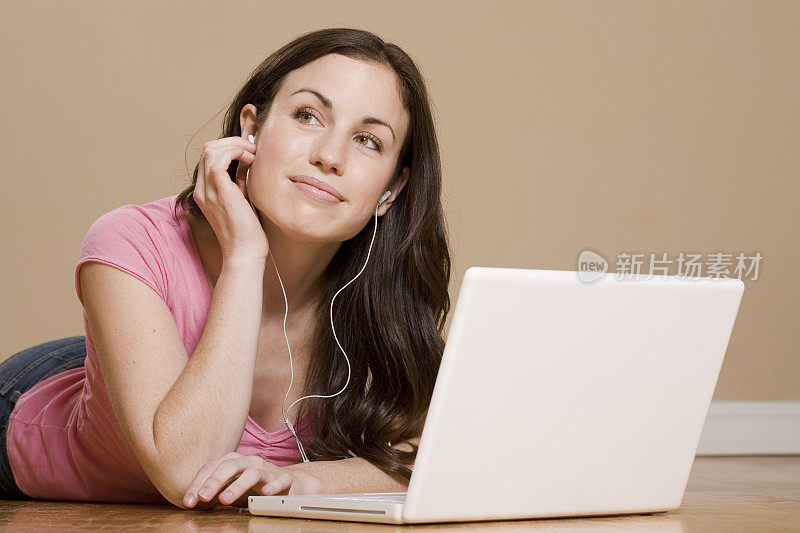年轻女子微笑着在电脑上听音乐