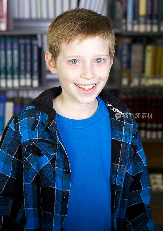 可爱的男孩在图书馆的书前微笑