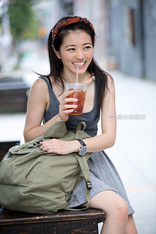 年轻女子在街上喝冰茶