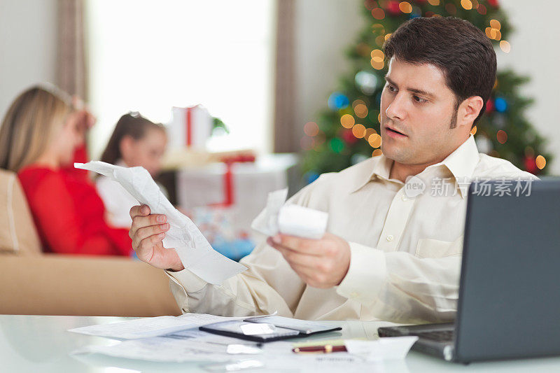 一个试图付圣诞节账单的人，身后还有家人。