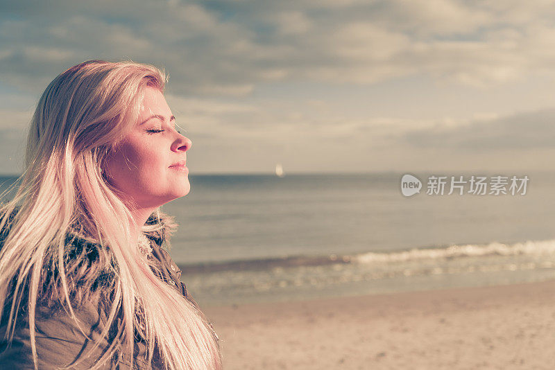 在寒冷的日子里，在海滩上放松的女人