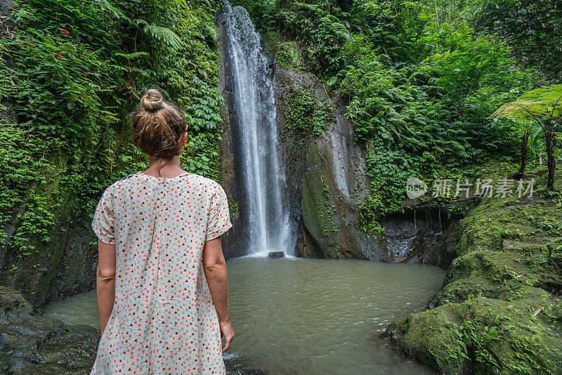 年轻女子在巴厘岛凝望美丽的瀑布