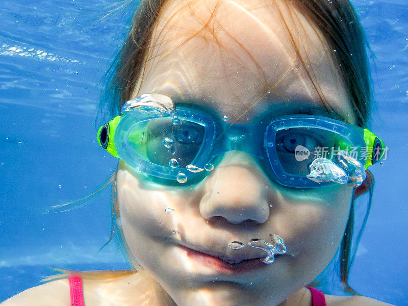 一个戴氧气罩的女孩在泳池里潜水