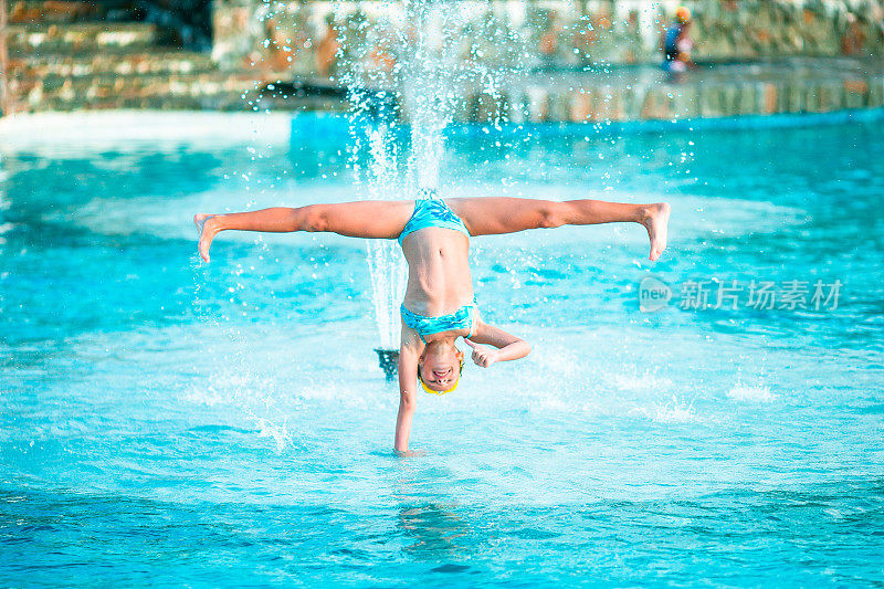 快乐的小女孩在游泳池享受假期。运动小孩在泳池边翻跟斗