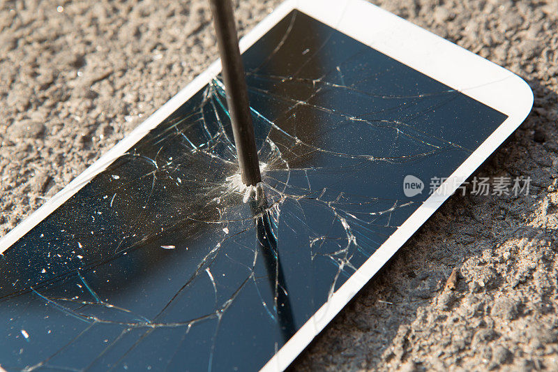 金属钉子和智能手机和一个破碎的屏幕在石头表面。力量的概念。