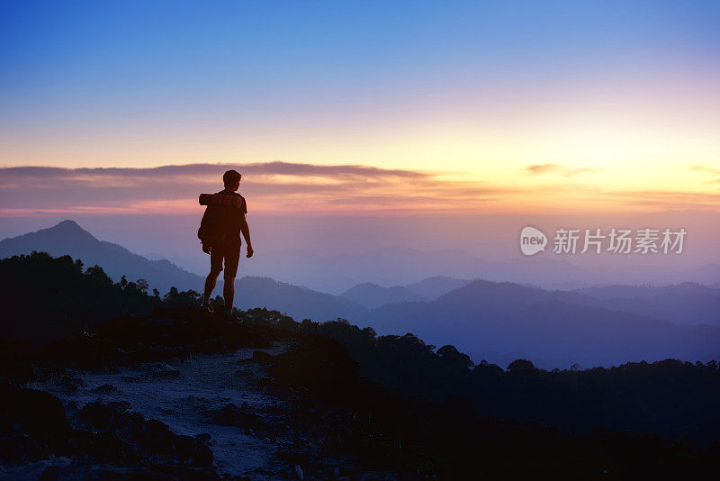 男人的剪影在夕阳山的背景