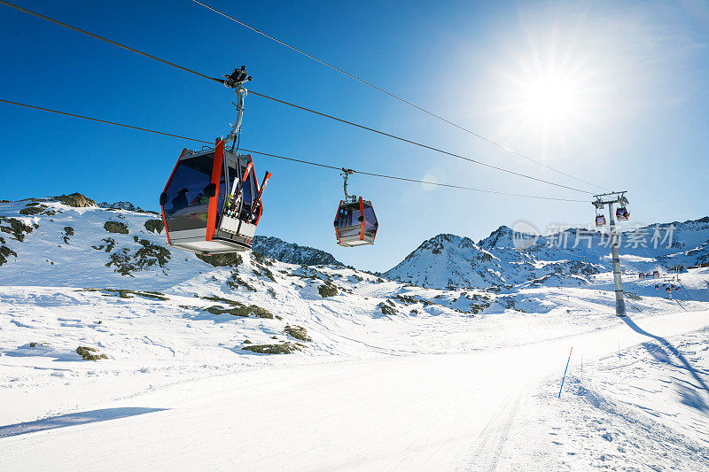在意大利阿尔卑斯的一个阳光明媚的冬日里，滑雪胜地的斜坡上，蓝天映衬下的滑雪缆车