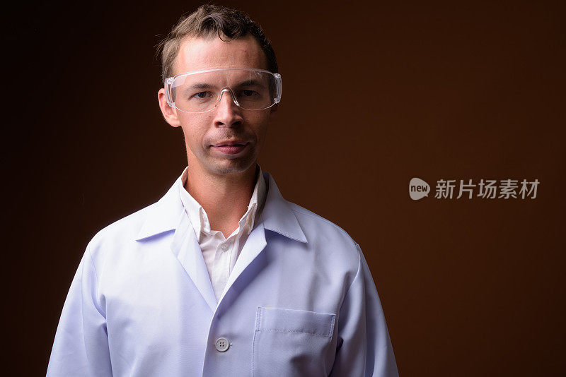 摄影棚拍摄的男医生戴着保护眼镜，反对彩色背景