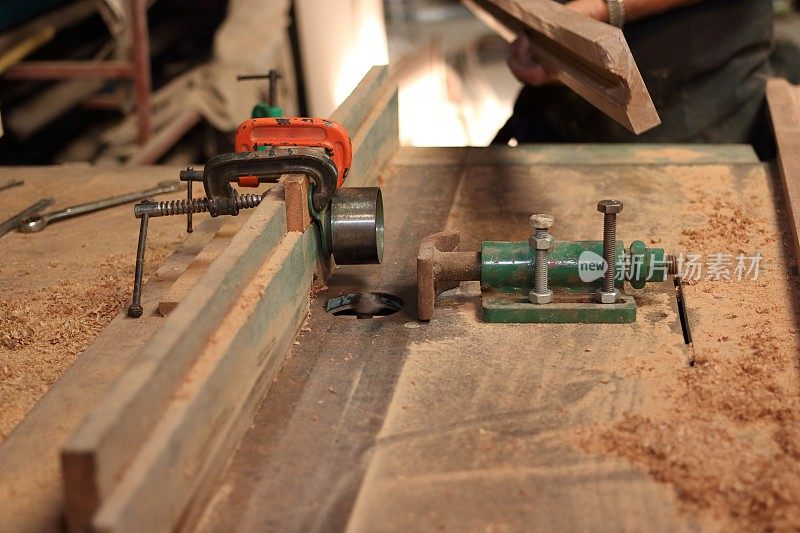 在木工车间里，工人正在准备刨削木板前的刨削台。选择性聚焦和浅景深。