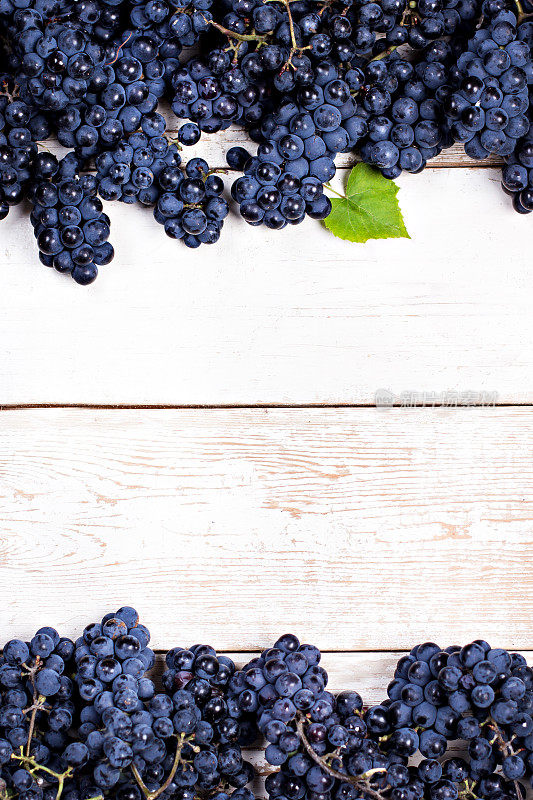 白色旧木板上的蓝葡萄。