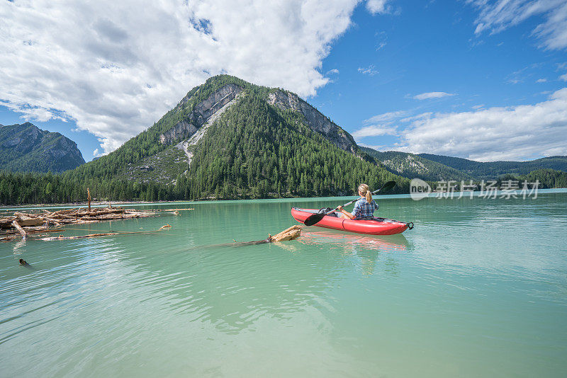 山上的女孩在山上的湖上划着红色的独木舟