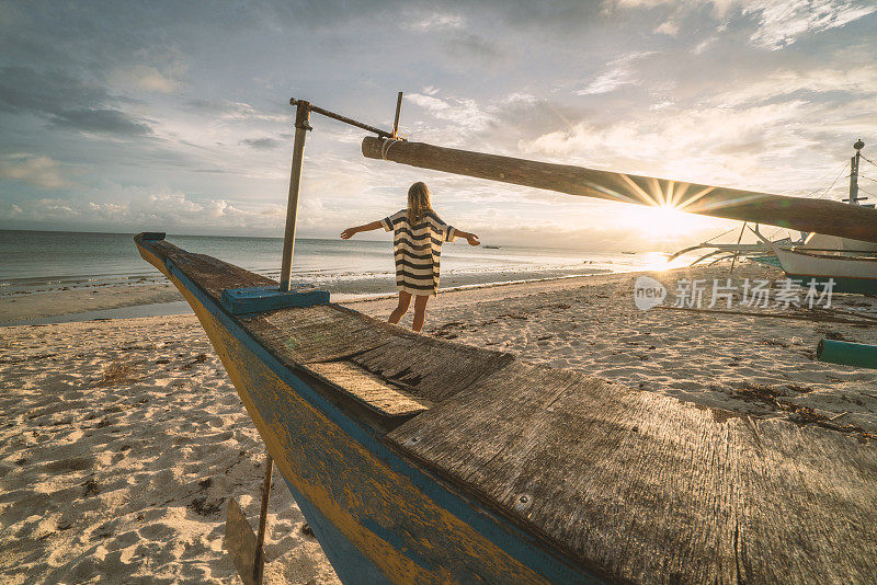 年轻女子在热带岛屿上拥抱生命张开双臂在日落，度假海滩