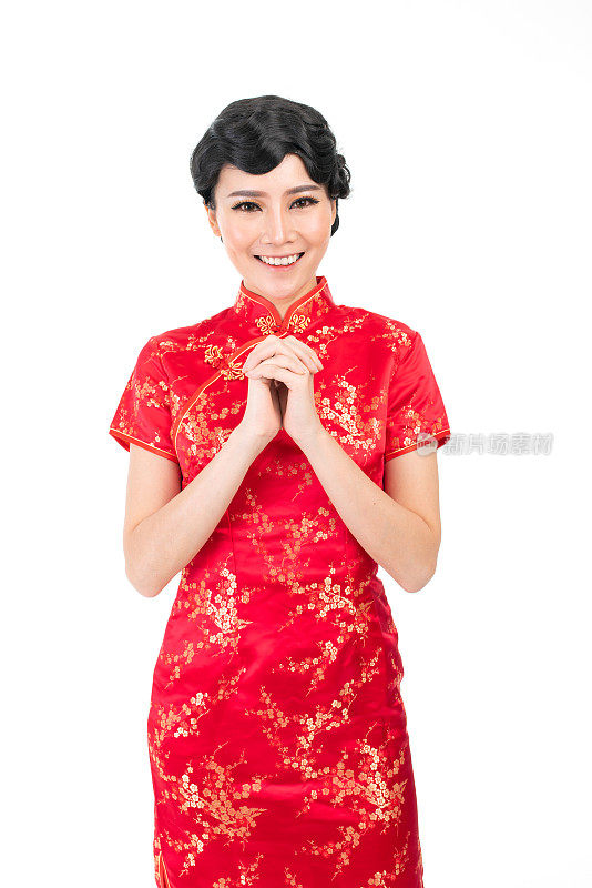 亚洲华人穿着中国传统服装旗袍，摆出中国新年问候的架势
