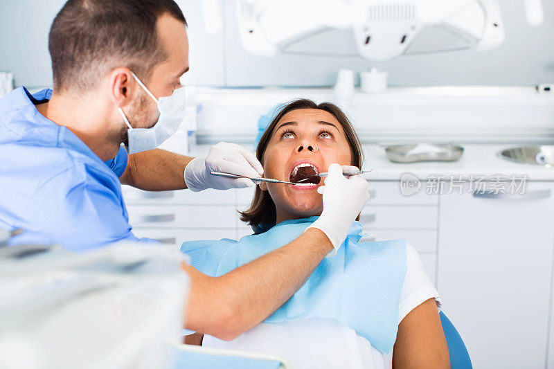 牙医正在治疗一位坐在牙科椅上的女病人