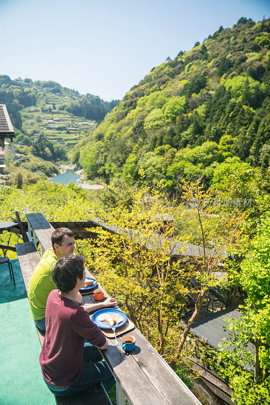 两个朋友在山里一家旅馆的露台上吃早餐