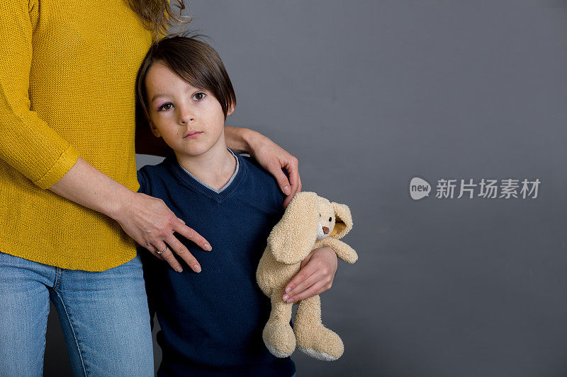 眼睛受伤的伤心男孩，在家里拥抱妈妈和泰迪熊