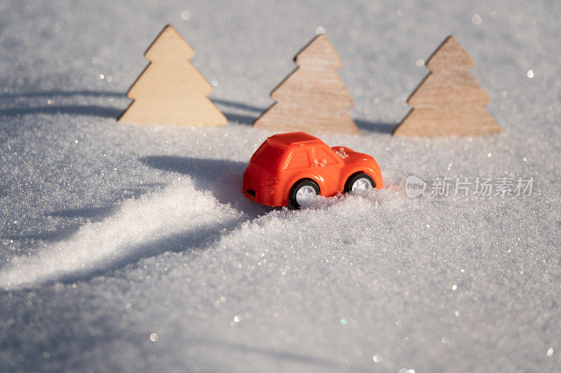 一辆玩具复古车在雪地里的轨迹。在汽车的后面有一个红色的新年球。极简主义理念，60年代风格。节日快乐贺卡