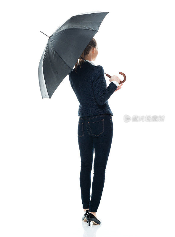 白人年轻女商人站在白色背景下穿着西装，拿着雨伞