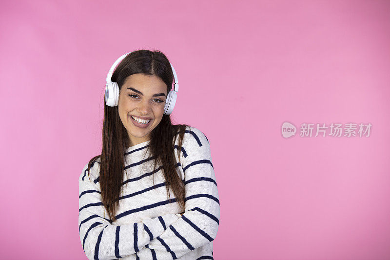戴着白色耳机的女人在欣赏粉色背景的音乐