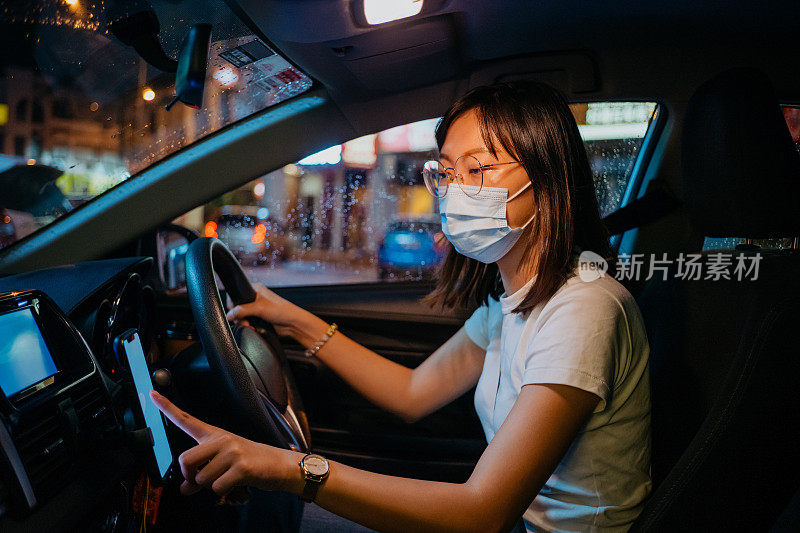 亚洲女性网约车司机戴着口罩使用智能手机