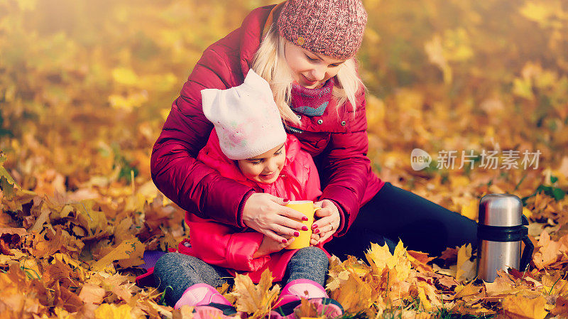 秋天，在公园里，母子从保温瓶里倒茶或咖啡。妈妈女儿从保温瓶里倒咖啡或茶