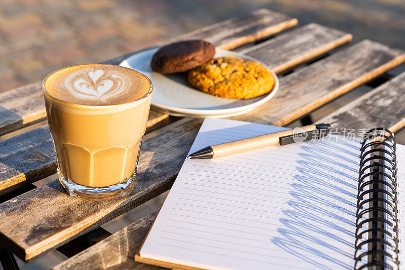 咖啡和笔记本放在一张木桌上。