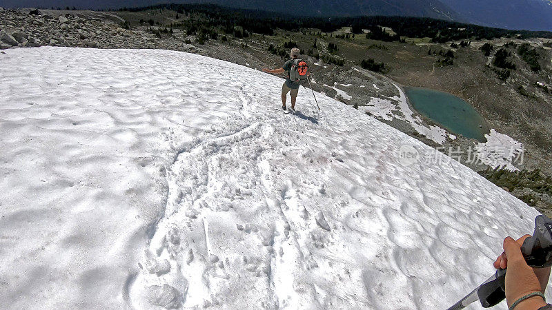 徒步旅行者沿着积雪的山坡跑下去