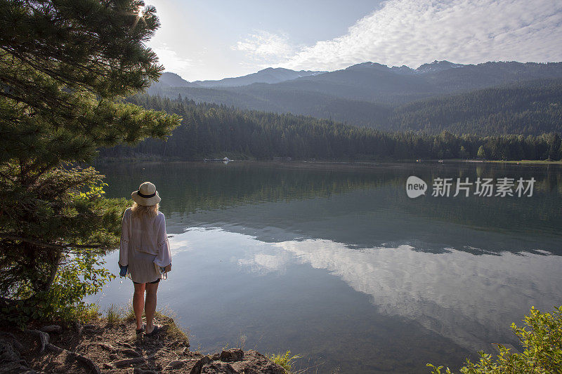 成熟的女人带着书和水瓶，停在湖边