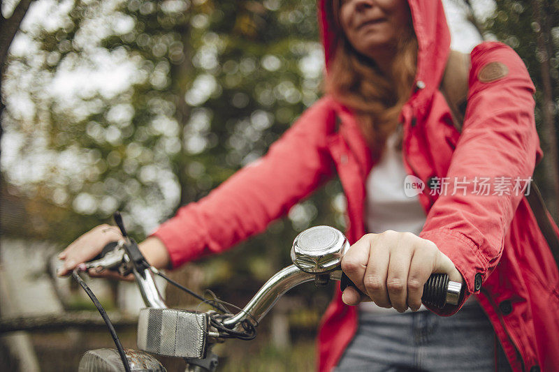 在雨中骑车——一位橙色头发、红色雨衣的年轻女子在雨中骑自行车
