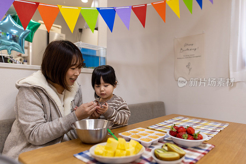 年轻的母亲和她的小女儿在家里做馅饼