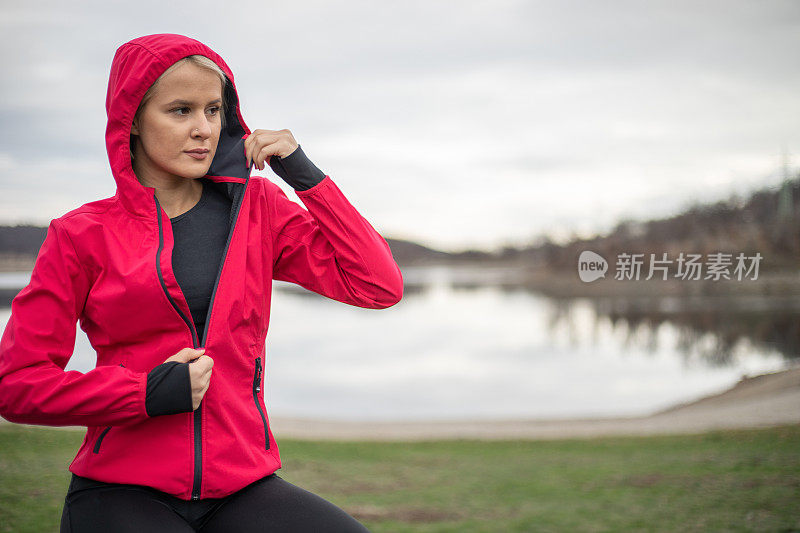 运动的女人。放一件运动夹克。一位年轻貌美的女子，穿着运动夹克，准备进行户外训练