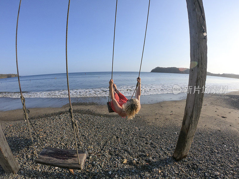 看女人享受海边荡秋千在早上