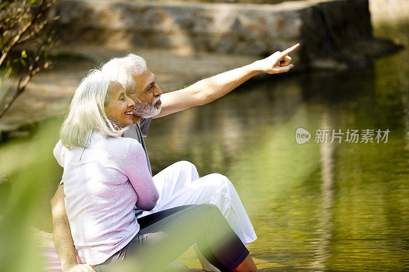 一对老年夫妇在湖边欣赏风景